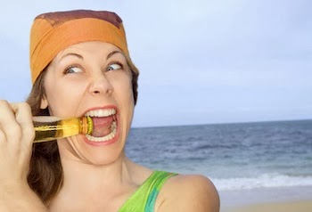 woman at beach using teeth to open beer bottle