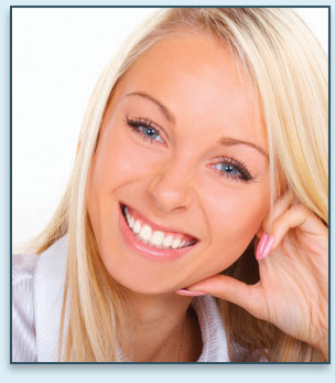 A person with long blonde hair and pink nails smiles into the camera.