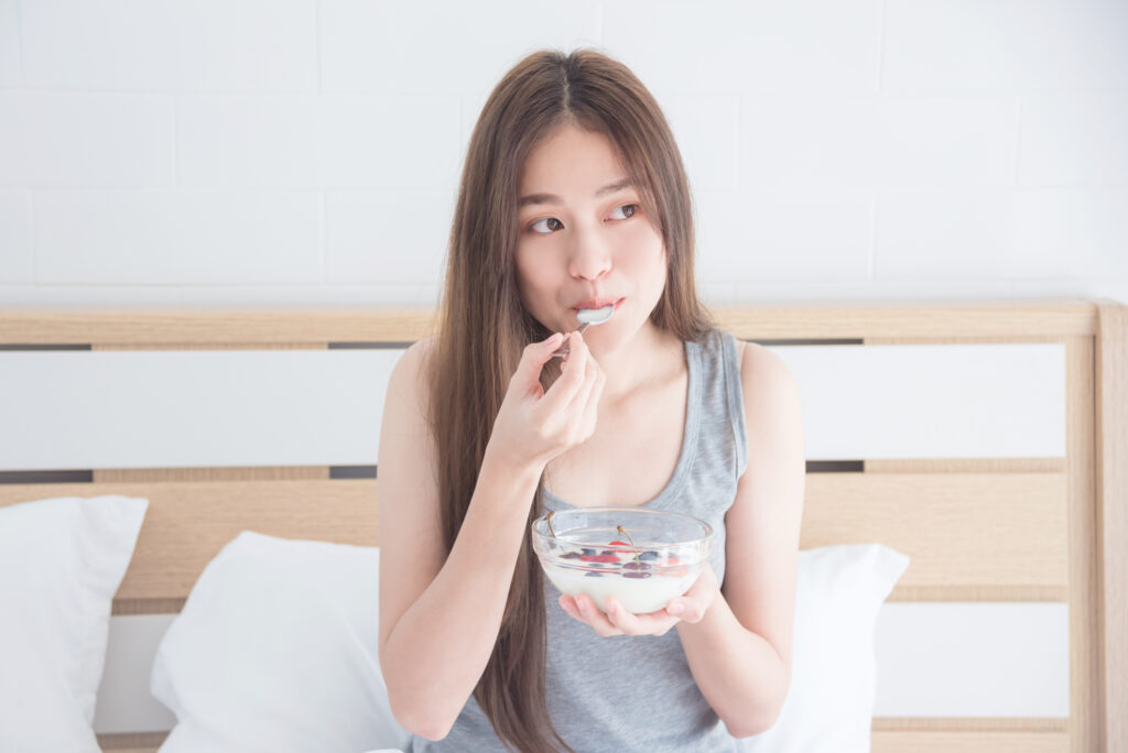 Woman eating yogurt with fruits for breakfast