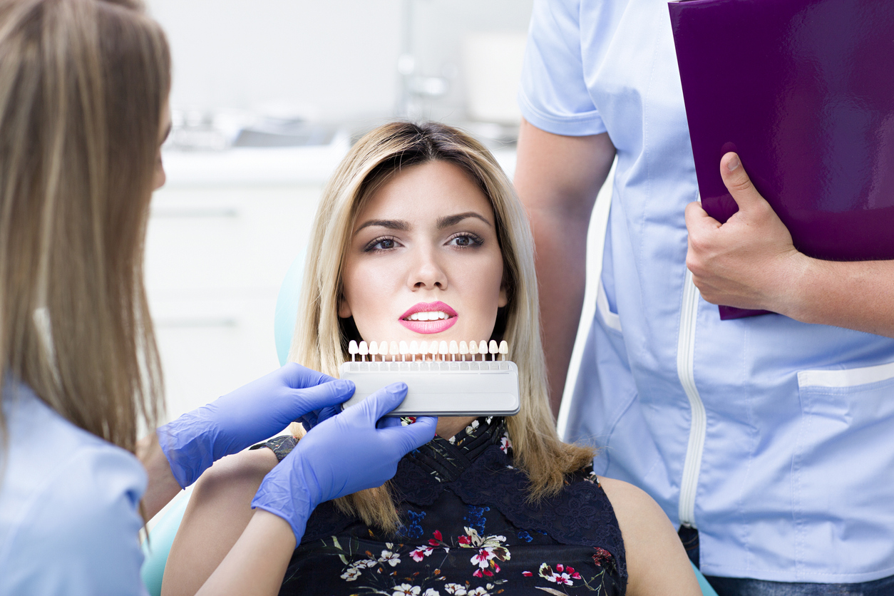A dentist shows their patient teeth whitening options.