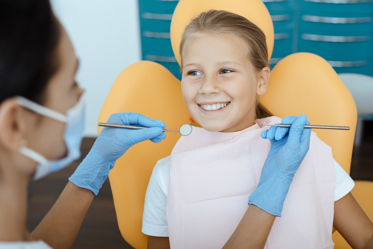 A child smiles at their dentist during a dental exam.