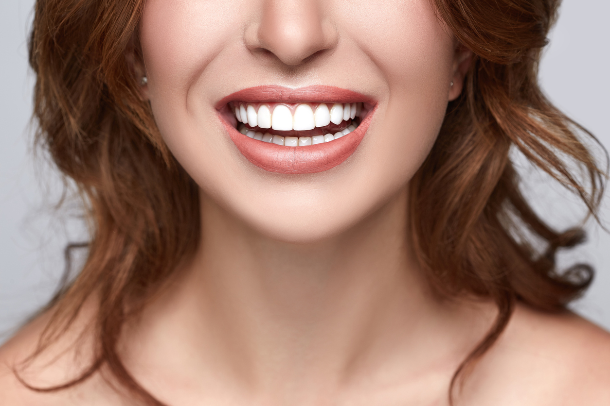 A person with healthy white teeth smiles into the camera.