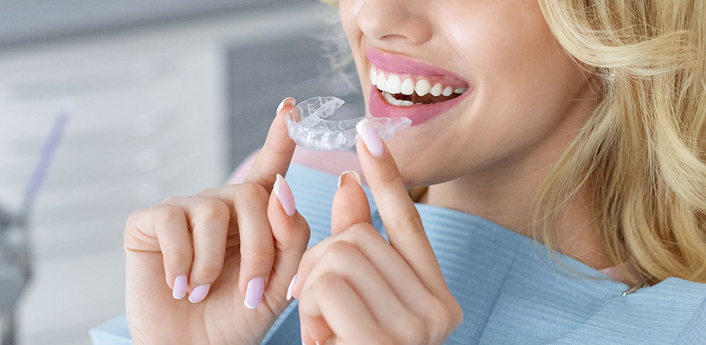 A person removes an Invisalign clear aligner from their mouth.