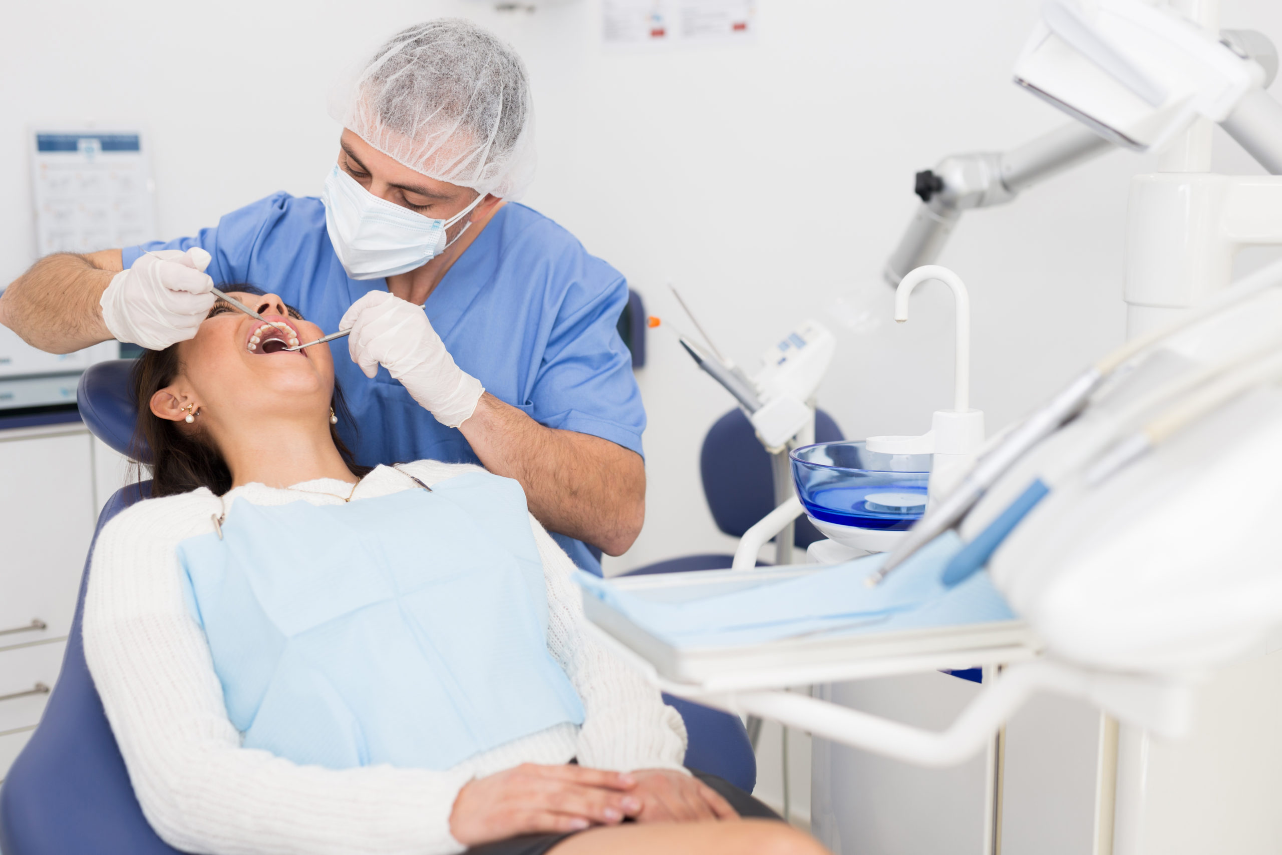 A dentist evaluates a patient's teeth in a dental office.